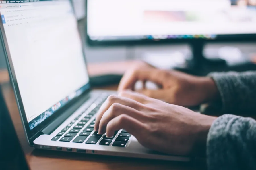 Hands working at a laptop keyboard